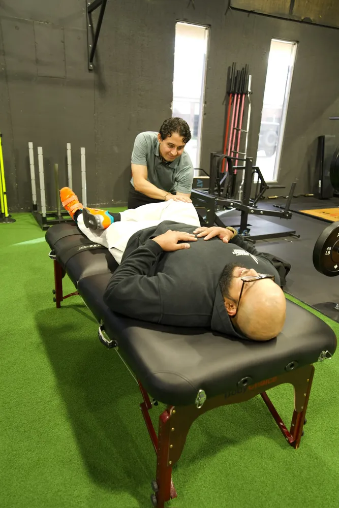 Physiotherapist treating a patient's leg on a treatment table in a rehabilitation space