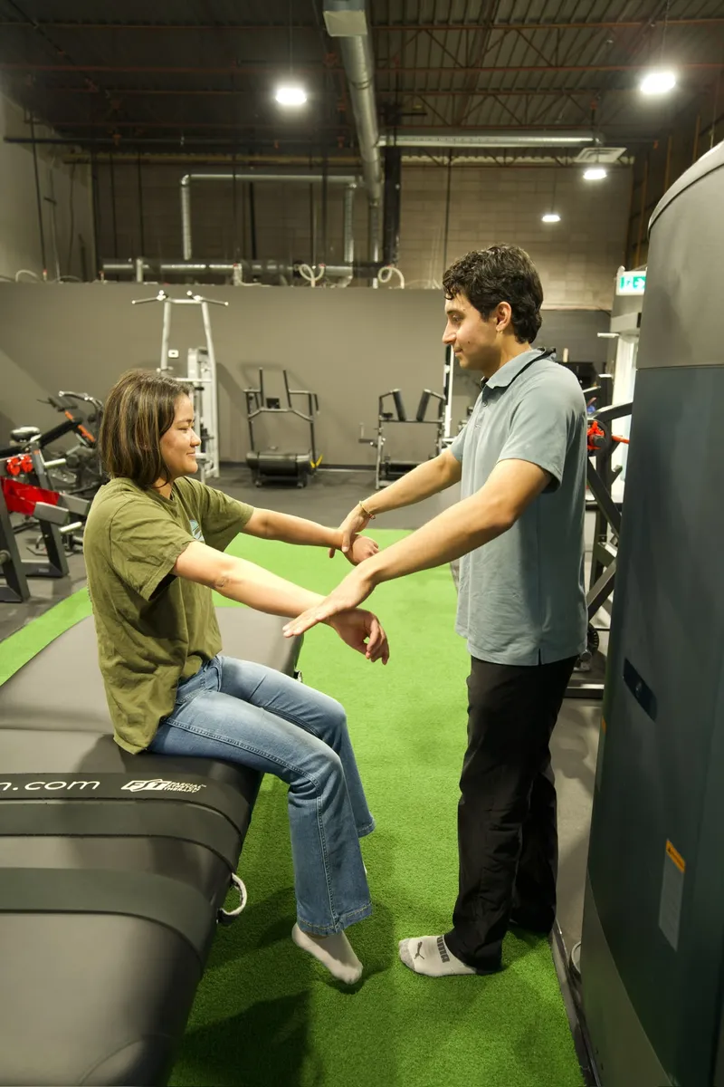 Physiotherapist assessing a standing patient's wrist and arm